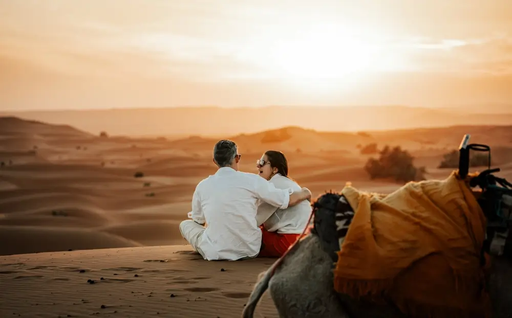 Travellers watching the sun set over the Erg Chebbi dunes