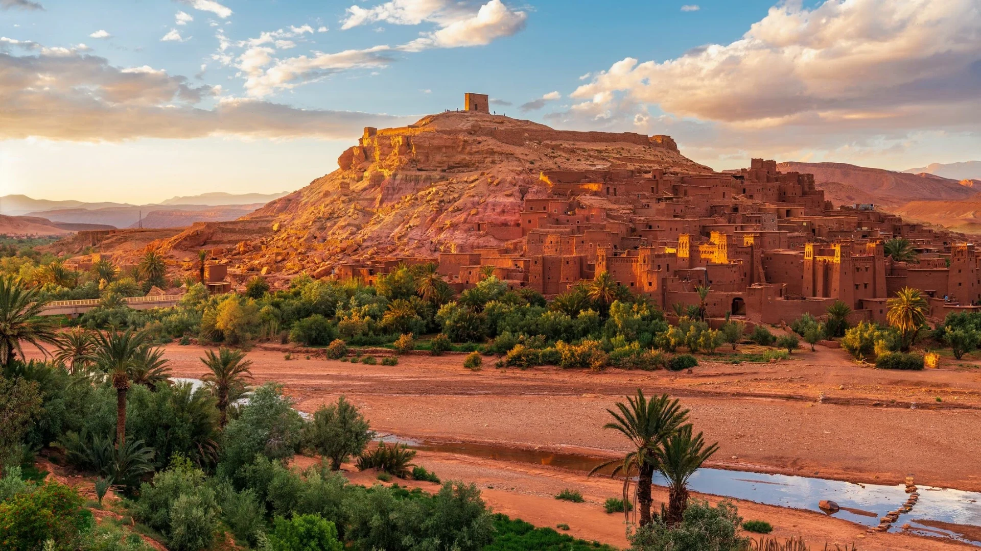 Ait Ben Haddou earthen kasbah near Ouarzazate glowing at sunset above the palm groves